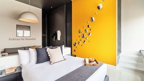 Un dormitorio moderno con cama, mesitas de noche, un espejo montado en la pared y una pared de acento amarilla con espejos decorativos.