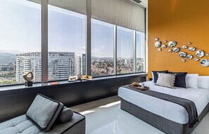A modern bedroom with a large window, a bed, a sofa, and a wall with decorative mirrors. - Kukun Escape Santa Fe (Mexico City)