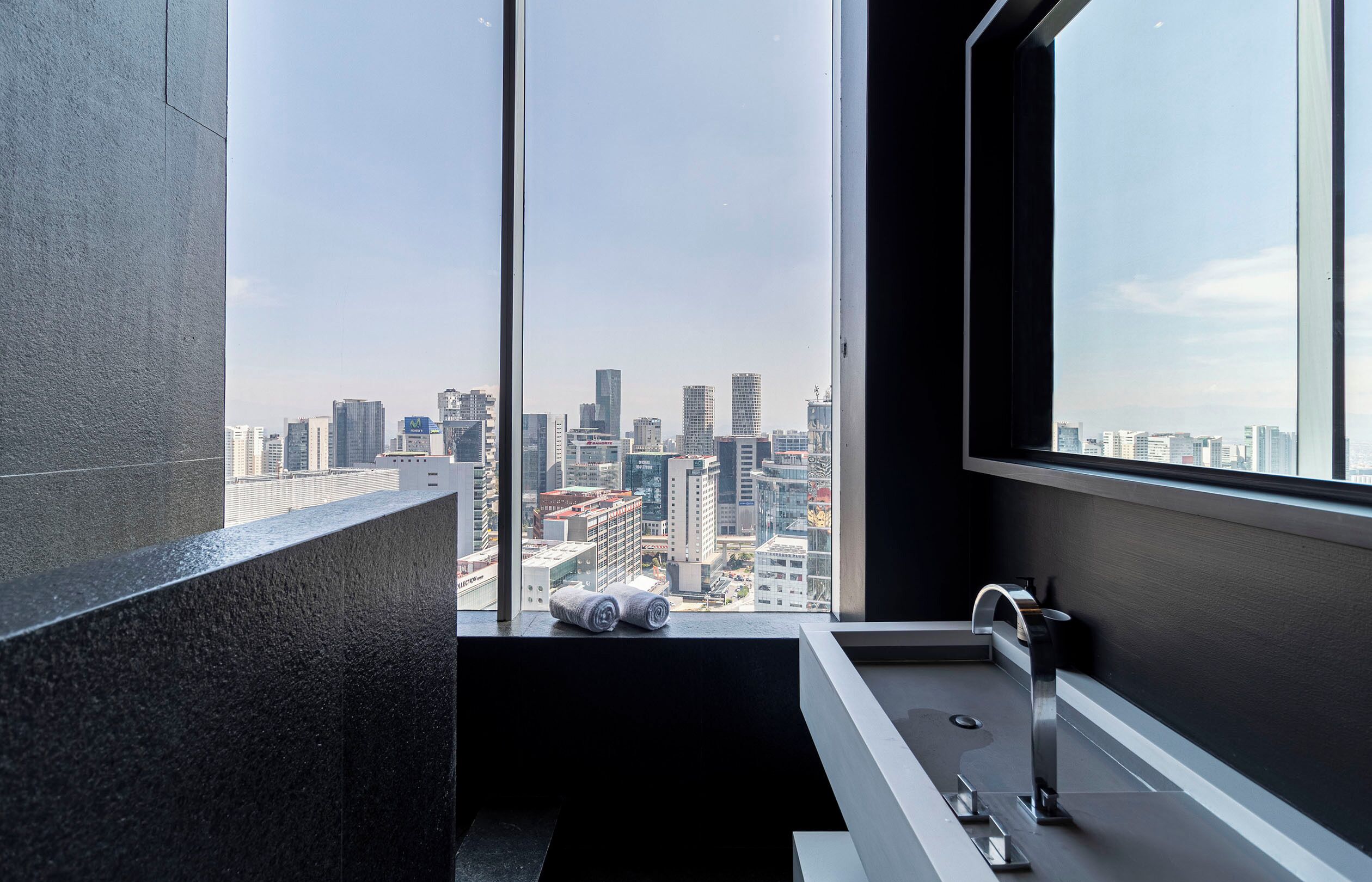 A modern bathroom with a large window, a bathtub, and a toilet.