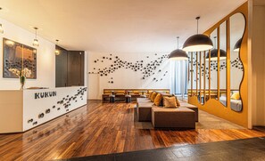 A modern hotel lobby with a reception desk, seating area, and decorative wall art. - Kukun Escape Santa Fe (Mexico City)