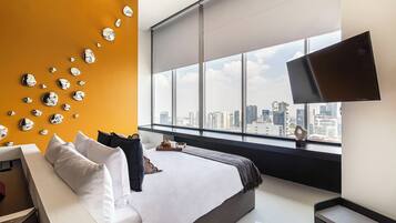 A modern hotel room with a large bed, a city view, and a wall with reflective spherical decorations.