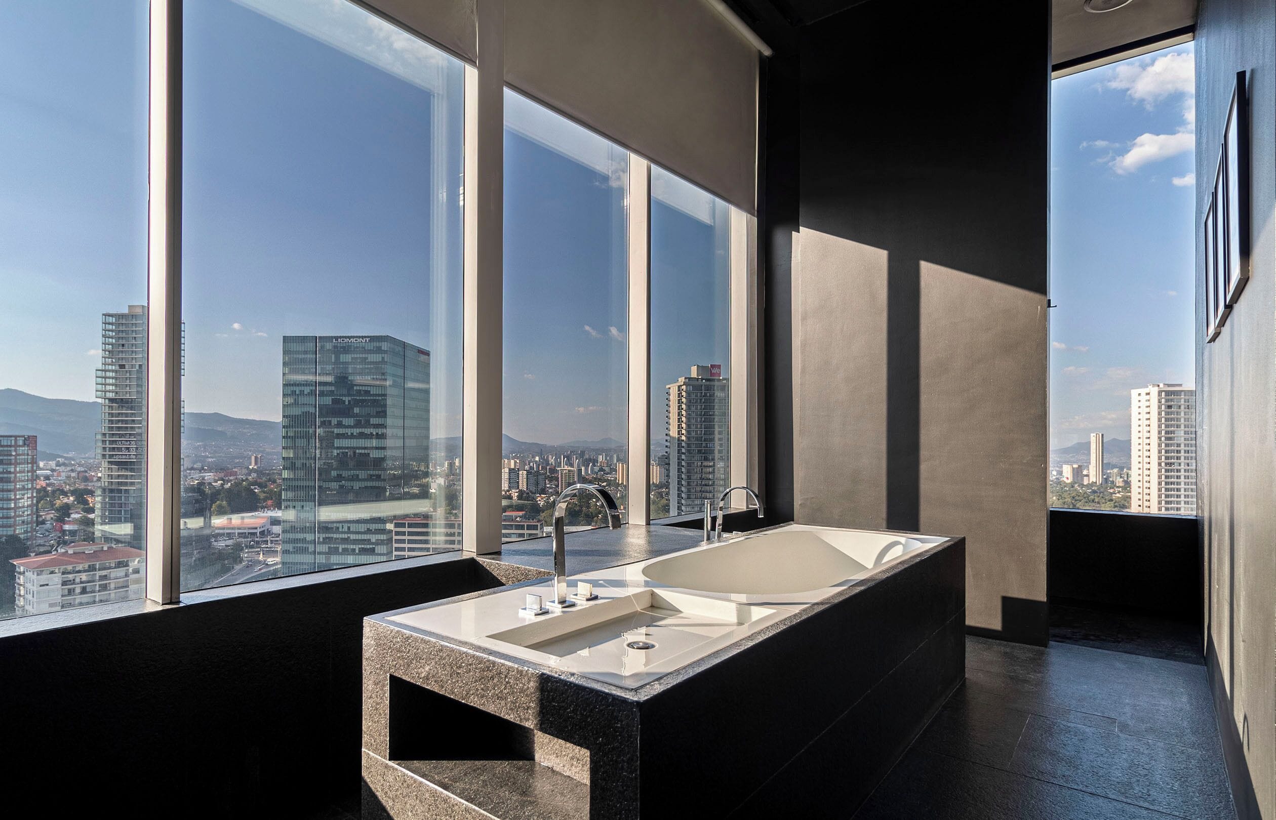 Un baño moderno con una bañera grande, un lavabo y una ventana con vistas a la ciudad.
