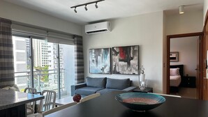 Un salon moderne avec un canapé, une table à manger et des chaises, ainsi qu’une grande fenêtre.