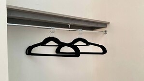 A closet with two black hangers on a rod. - Newport City Escape - 2 Bedroom Apartment (Newport)