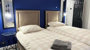 Ein Schlafzimmer mit zwei Betten, einem Spiegel, einem kleinen Tisch und einer Tür.
