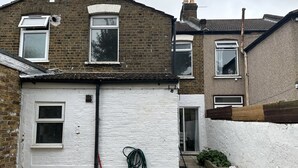 En bostadsbyggnad med en vit fasad, en tegelbeklädd framsida och flera fönster.