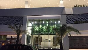 A modern building with a glass facade, palm trees in front, and the name "ARPELO" visible on the entrance.
