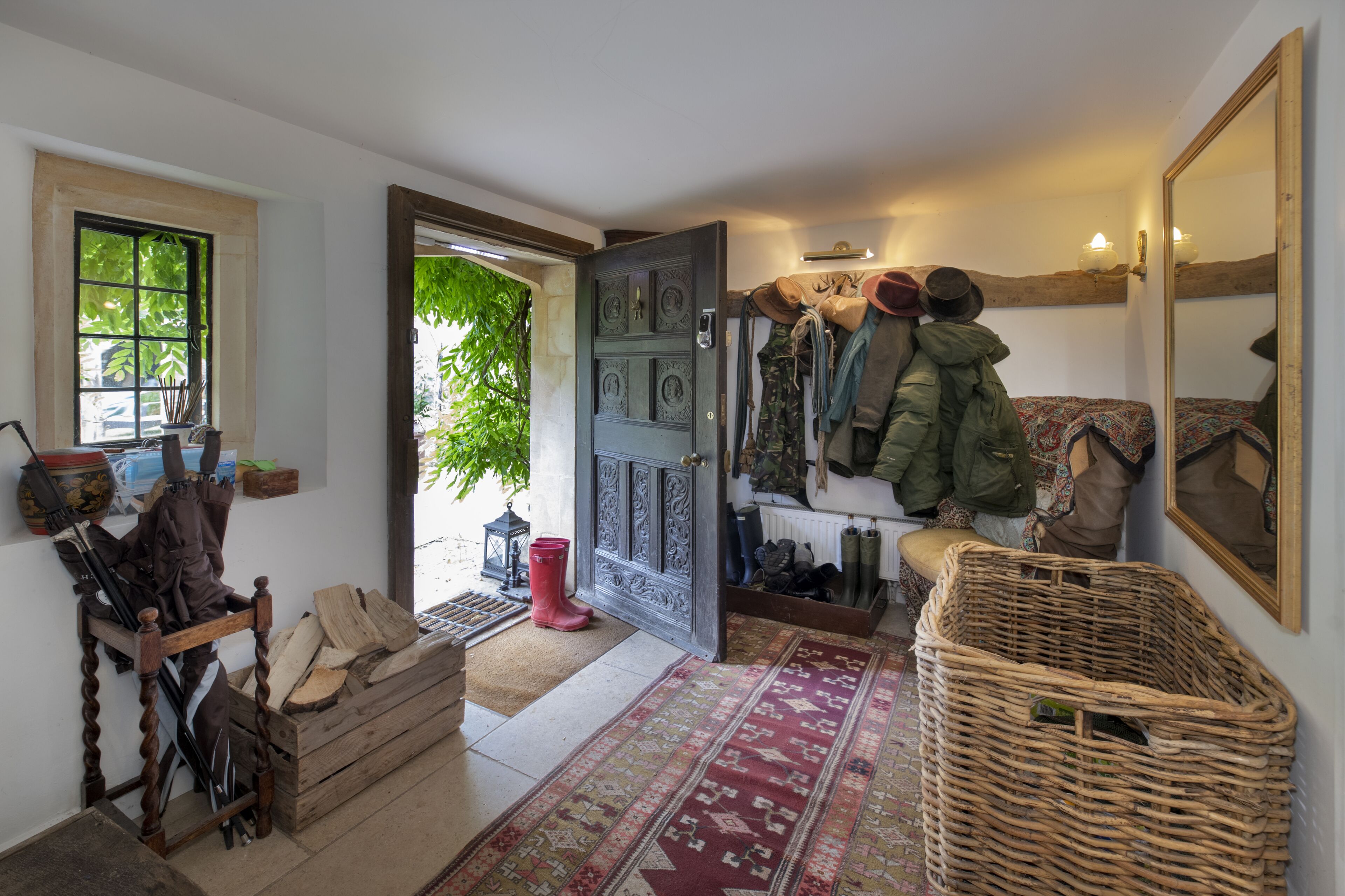 A cozy entryway with a wooden bench, a red door, and a patterned rug.