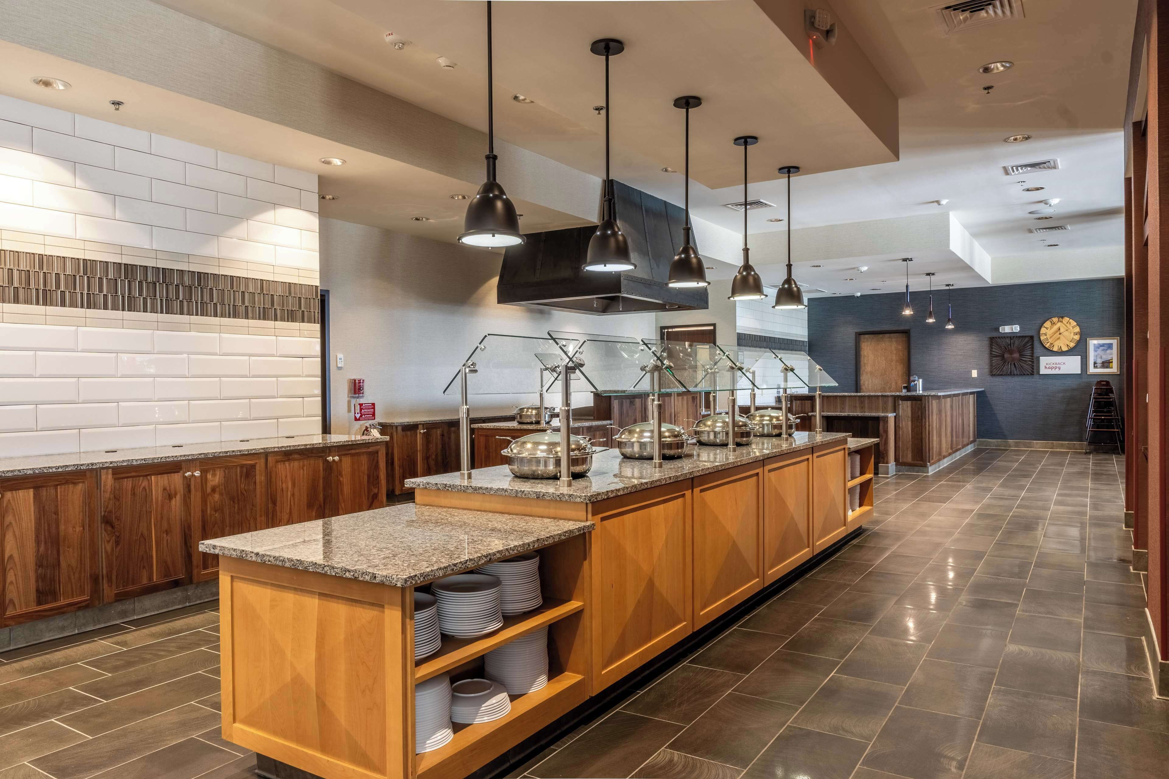 Cocina moderna con encimeras de granito, armarios de madera y electrodomésticos de acero inoxidable.