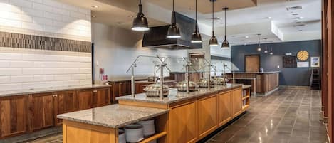 Cocina moderna con encimeras de granito, armarios de madera y electrodomésticos de acero inoxidable.