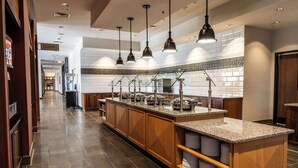 A modern kitchen with granite countertops, wooden cabinets, and pendant lighting. - Drury Plaza Hotel Dallas Arlington (Arlington)