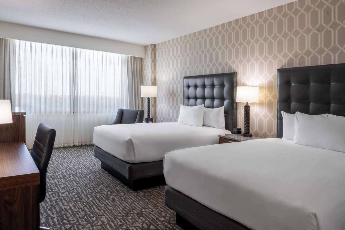 Ein Hotelzimmer mit zwei Betten, einem Schreibtisch und einem Stuhl.