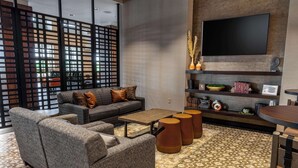 A modern living room with a sectional sofa, a coffee table, and a TV mounted on the wall. - Drury Plaza Hotel Dallas Arlington (Arlington)