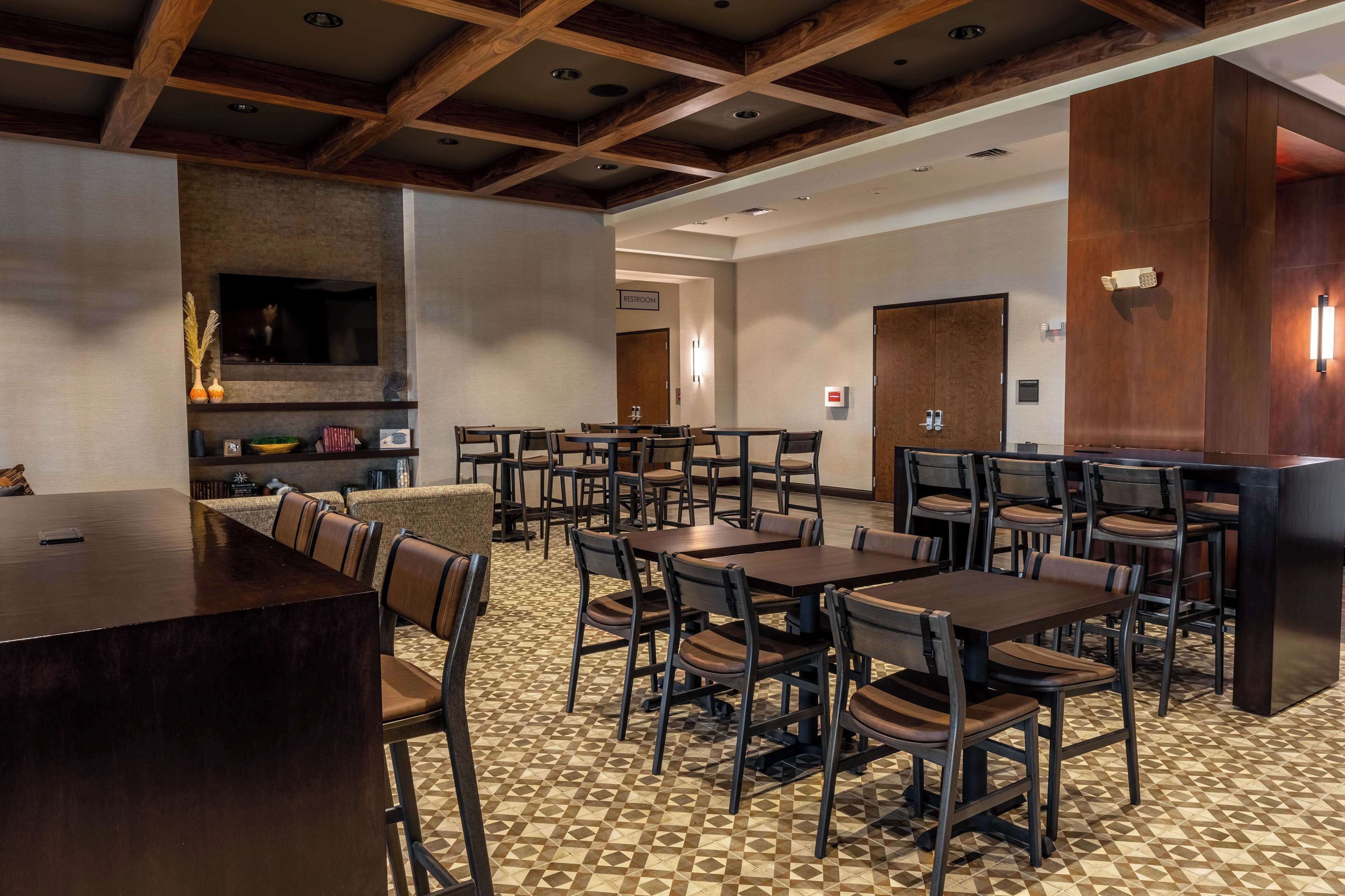 Une salle à manger d’hôtel avec plusieurs tables et chaises, une cheminée et un comptoir de cuisine.