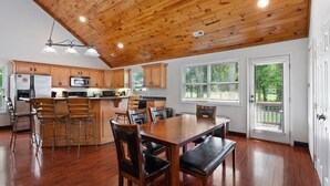 Una cocina amplia con armarios de madera, un refrigerador de acero inoxidable y un comedor con mesa y sillas de madera.
