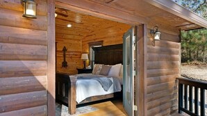 Ein Schlafzimmer einer Holzhütte mit Bett, Nachttischen und Wandleuchten.