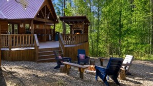 Eine Hütte mit einer Terrasse, Sitzgelegenheiten im Freien und einem Kamin.
