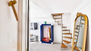 Een modern interieur met een trap, een grote spiegel en een kledingrek.