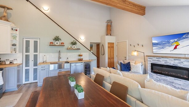 Un salon moderne avec une table à manger en bois, un canapé blanc et une cheminée.