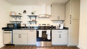 Una cocina moderna con electrodomésticos de acero inoxidable, armarios de colores claros y suelo de madera.