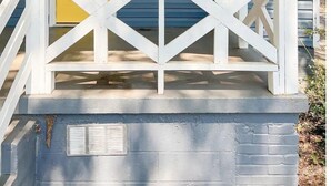 Una casa con una puerta amarilla, el número blanco '214' encima y una barandilla blanca en el porche.