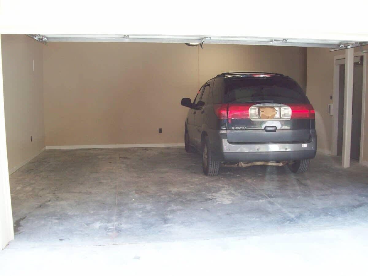 A car parked in a garage with a concrete floor and beige walls.