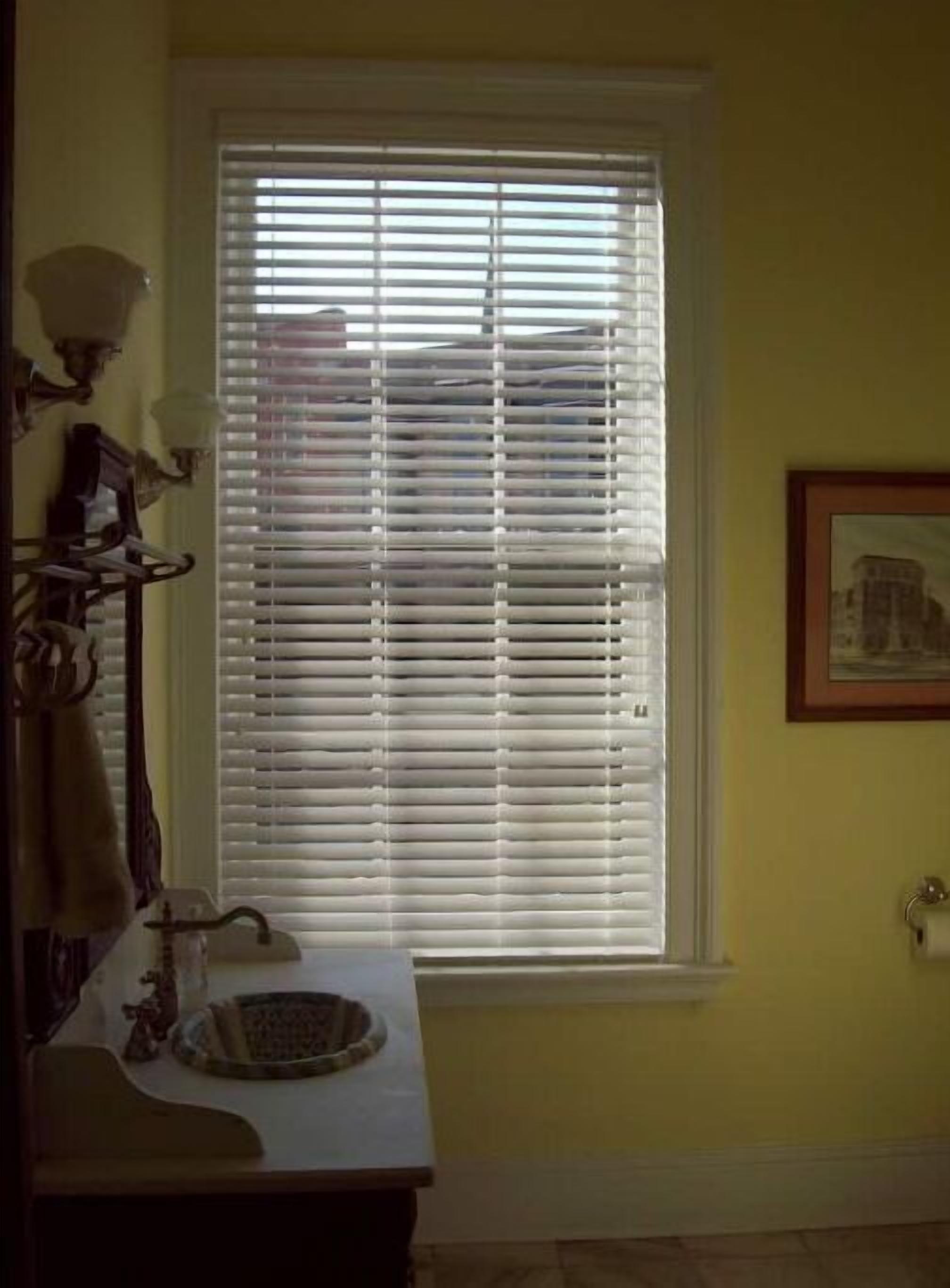 A bathroom with a window, a sink, and a towel rack.