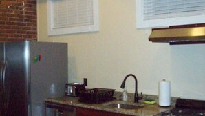 A compact kitchen with a refrigerator, stove, sink, and a small dishwasher. - Large Historic Downtown Loft - Rear (Macon)