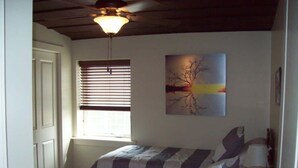 A bedroom with two beds, a ceiling fan, a window with blinds, and a painting on the wall. - Large, Unique, Ground Floor Loft with Parking #2 (Macon)
