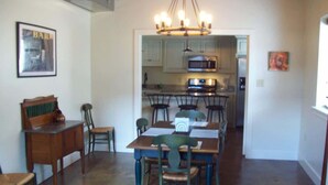 A dining area with a wooden table and chairs, a chandelier, and a kitchen in the background. - Large, Unique, Ground Floor Loft with Parking #2 (Macon)