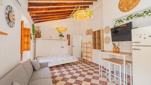 Um espaço de estar compacto com piso xadrez, um sofá, uma cama, uma televisão e teto de madeira.