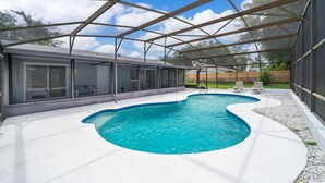 A covered swimming pool with a modern house in the background. - Four Season Home  (Kissimmee)