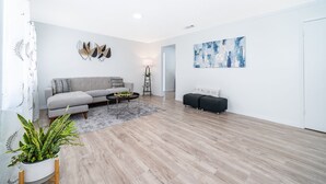 A modern living room with a grey sofa, a black ottoman, a coffee table, and a potted plant. - Four Season Home  (Kissimmee)