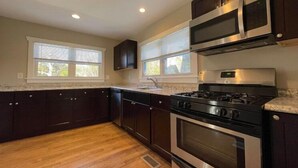 A modern kitchen with dark cabinetry, a stainless steel stove, and a microwave.