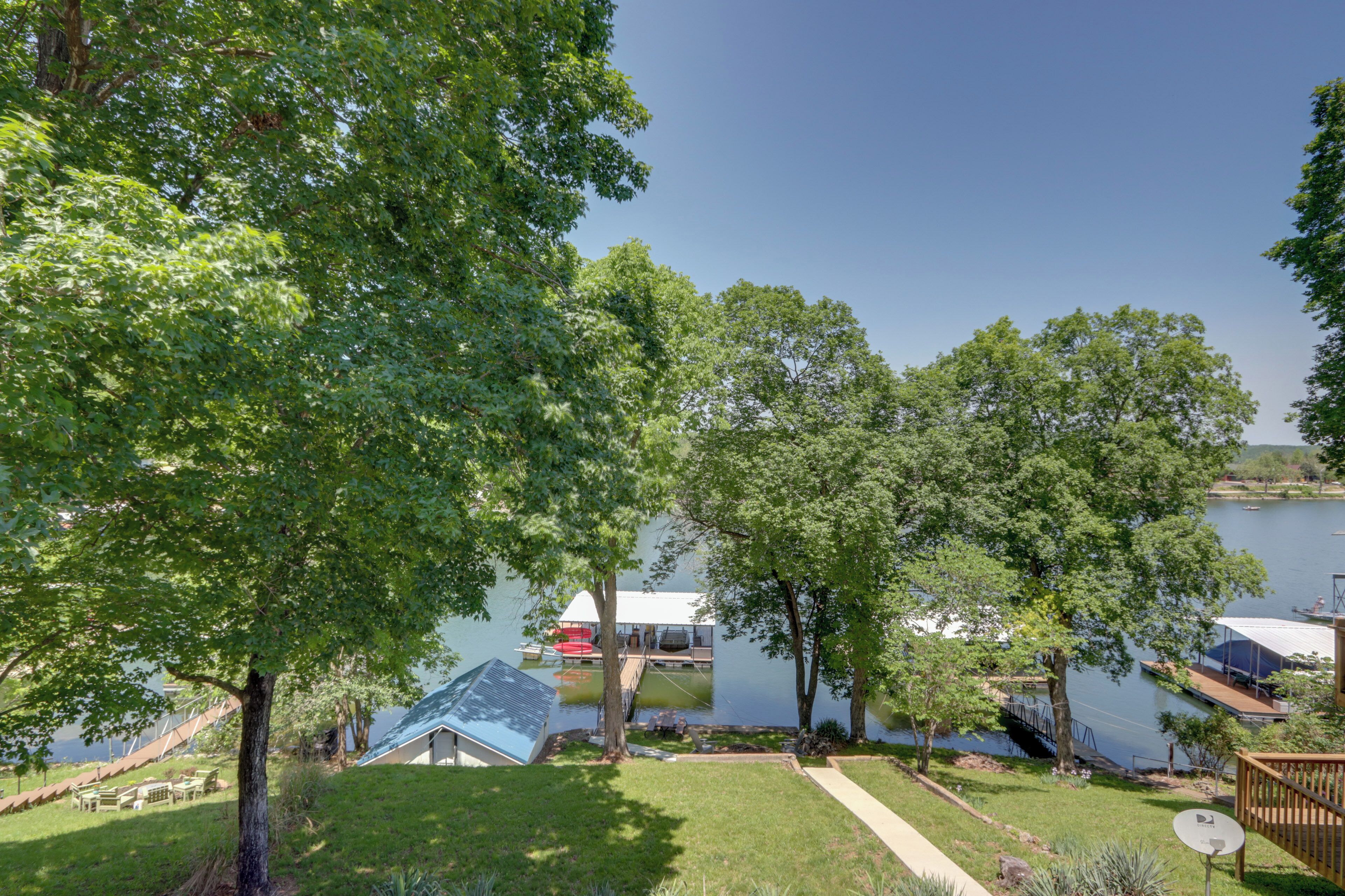 A lakeside property with a dock, a covered boat house, and a grassy area with a pathway.