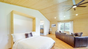 A bedroom with a bed, a sofa, wooden flooring, a ceiling fan, and a window. - Peaceful Purlear Vacation Rental w/ Creek Access! (Purlear)