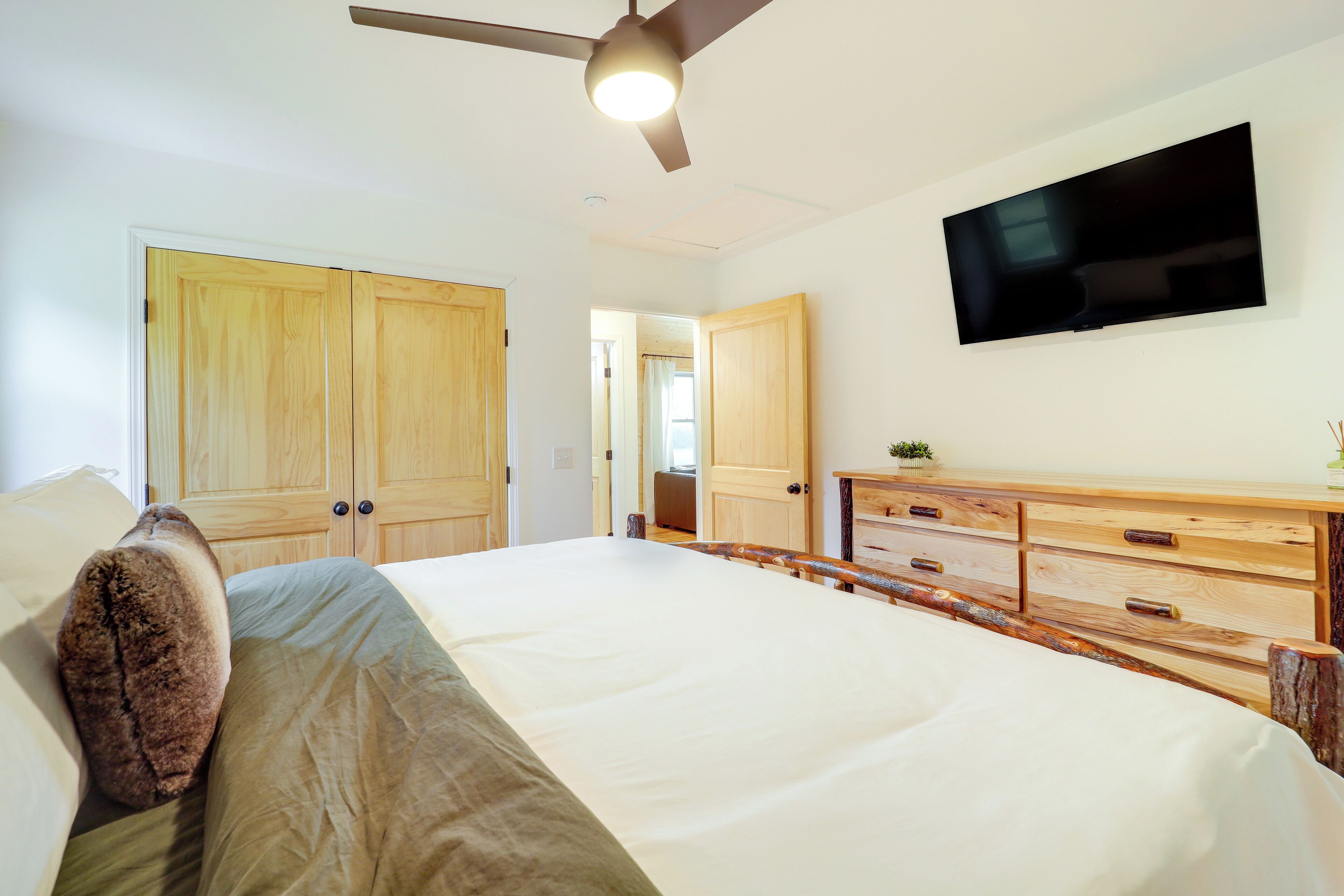 Un dormitorio con cama, armario de madera, televisor y ventilador de techo.