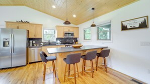 A modern kitchen with wooden cabinets, stainless steel appliances, and a central island with bar stools. - Peaceful Purlear Vacation Rental w/ Creek Access! (Purlear)