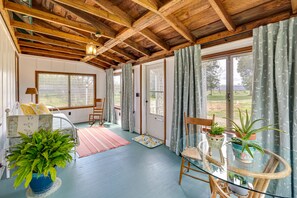 A room with a wooden ceiling, large windows, a glass table with plants, and a chair. - Country Getaway in Kinsale: Sunroom, Pond Access! (Kinsale)