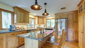 A kitchen with wooden cabinets, a granite countertop, stainless steel appliances, and pendant lighting. - Lakefront Connecticut Retreat Near Uconn (Coventry)