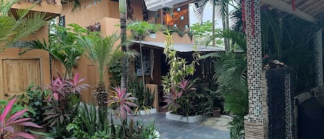 Un patio con plantas en macetas, piso de baldosas y un edificio de fachada también enlosetada.