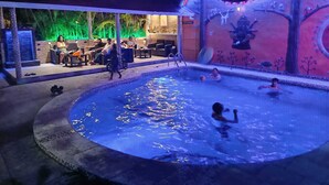 An outdoor pool area with people swimming and sitting around. - Casa Shangri La (Canoa)
