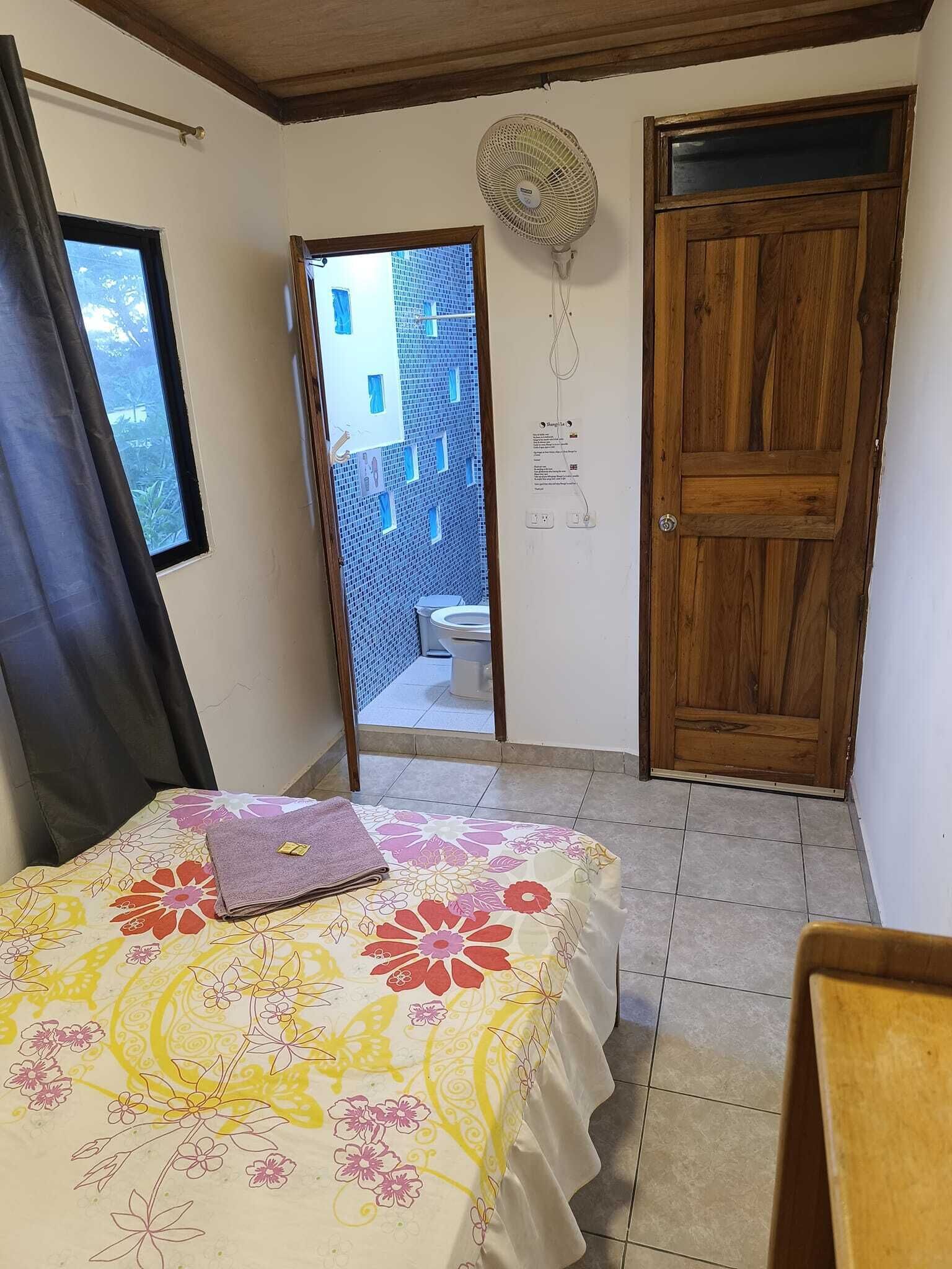 Un dormitorio con cama, una puerta de madera, un ventanal y vistas a un balcón.
