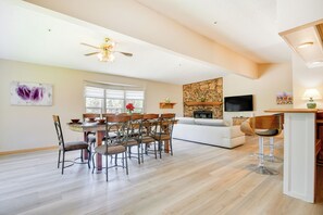 A spacious living room with a dining area, a stone fireplace, and a TV mounted on the wall. - Tranquil Maricopa Retreat w/ Pool + Hot Tub (Maricopa)