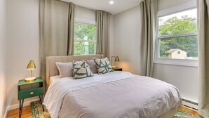 Ein Schlafzimmer mit Bett, Nachttischen und einem Fenster mit Vorhängen.