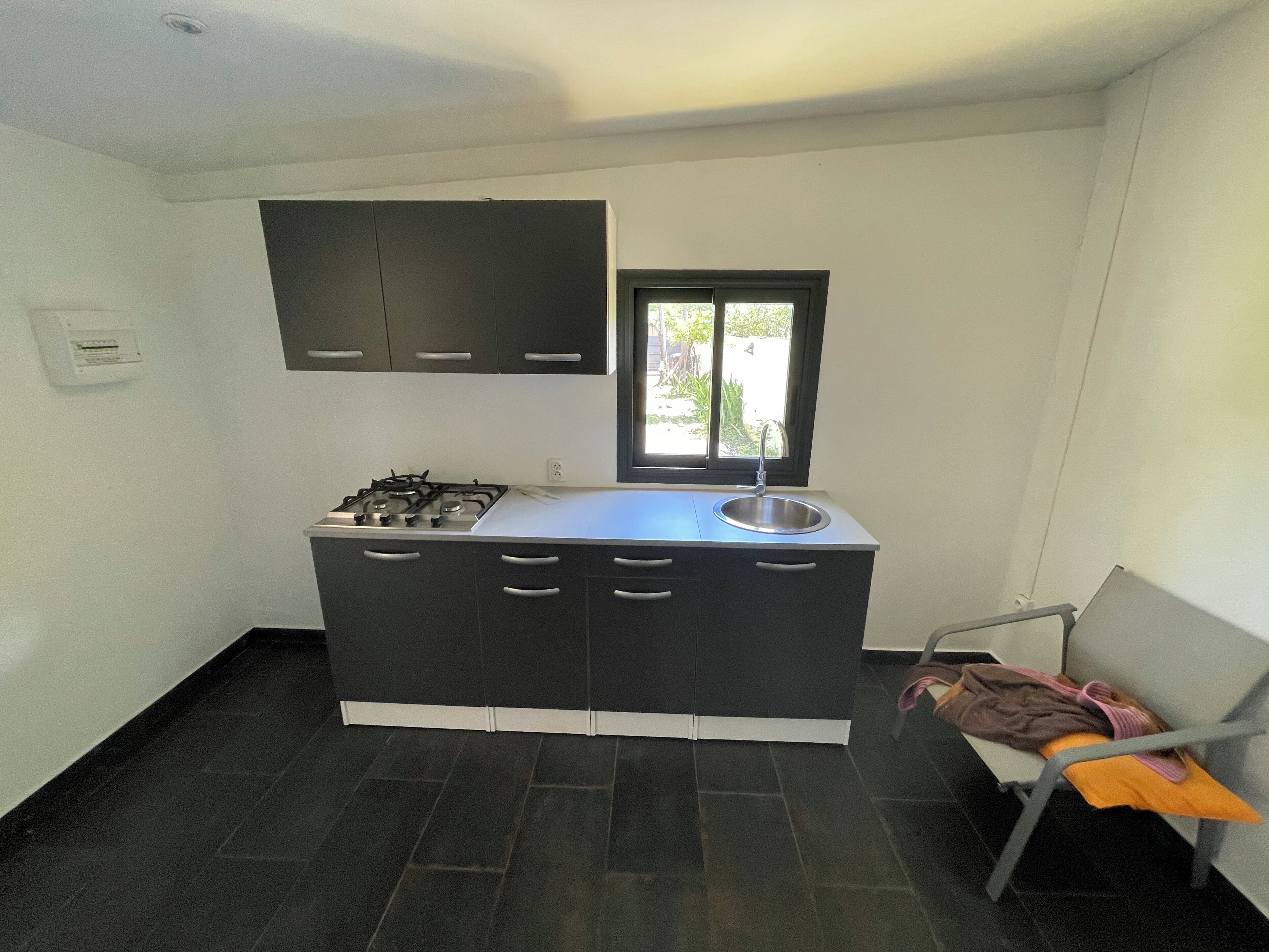 A compact kitchen with a gas stove, a sink, and dark cabinetry.