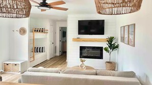 Een moderne woonkamer met een bank, televisie, open haard en plafondventilator.