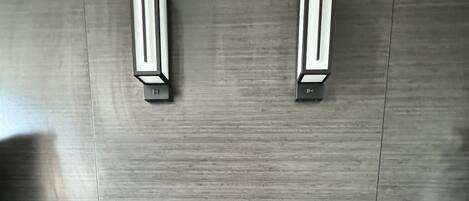 Habitación de hotel con cabecera de madera, dos lámparas de noche, teléfono junto a la cama y una mesita con toma de corriente.