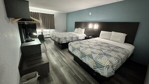 Ein Hotelzimmer mit zwei Betten, einem Schreibtisch, einem Fernseher und einer kleinen Mülltonne.