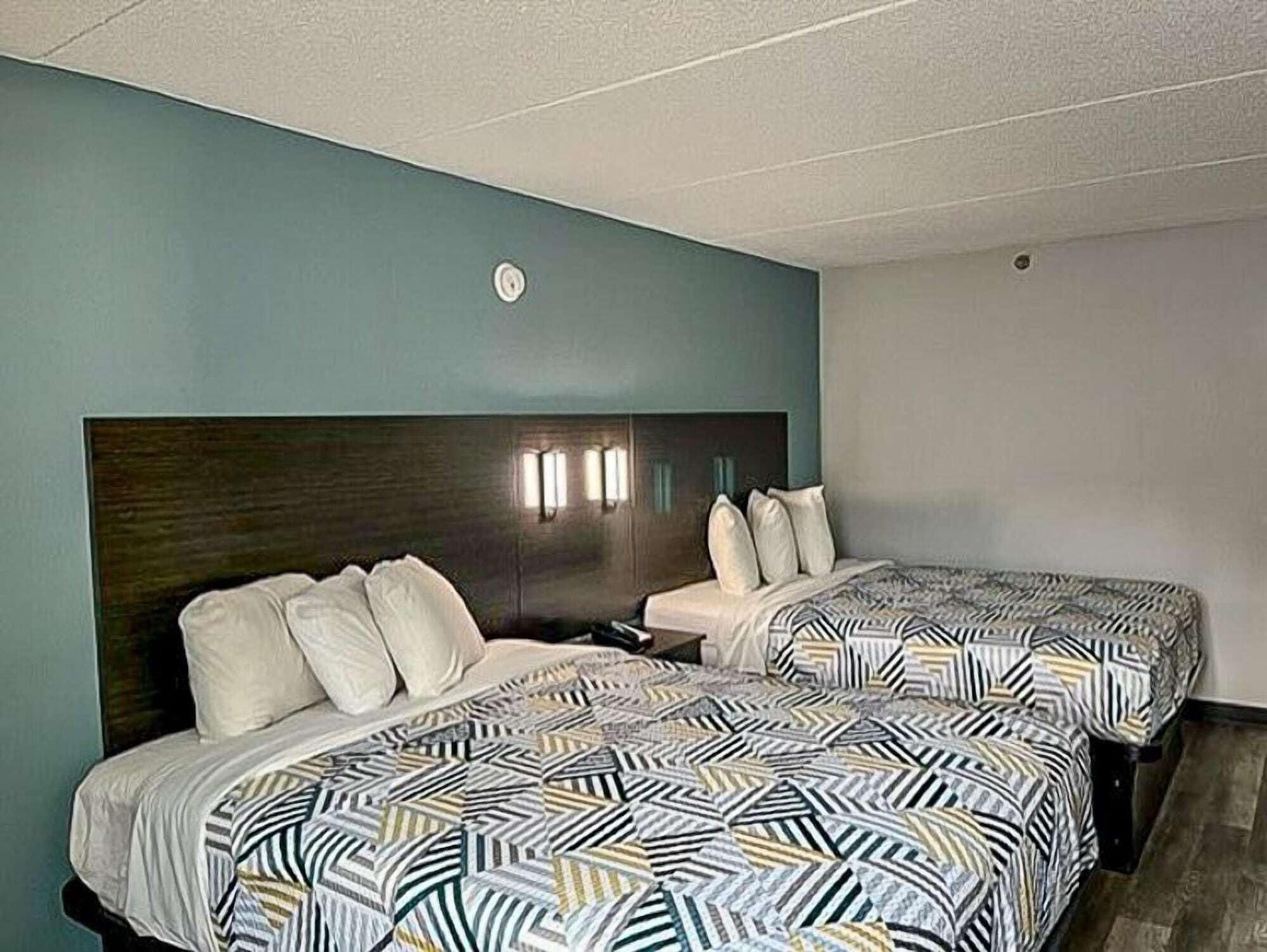 A hotel room with two beds, each with a patterned bedspread and white pillows.